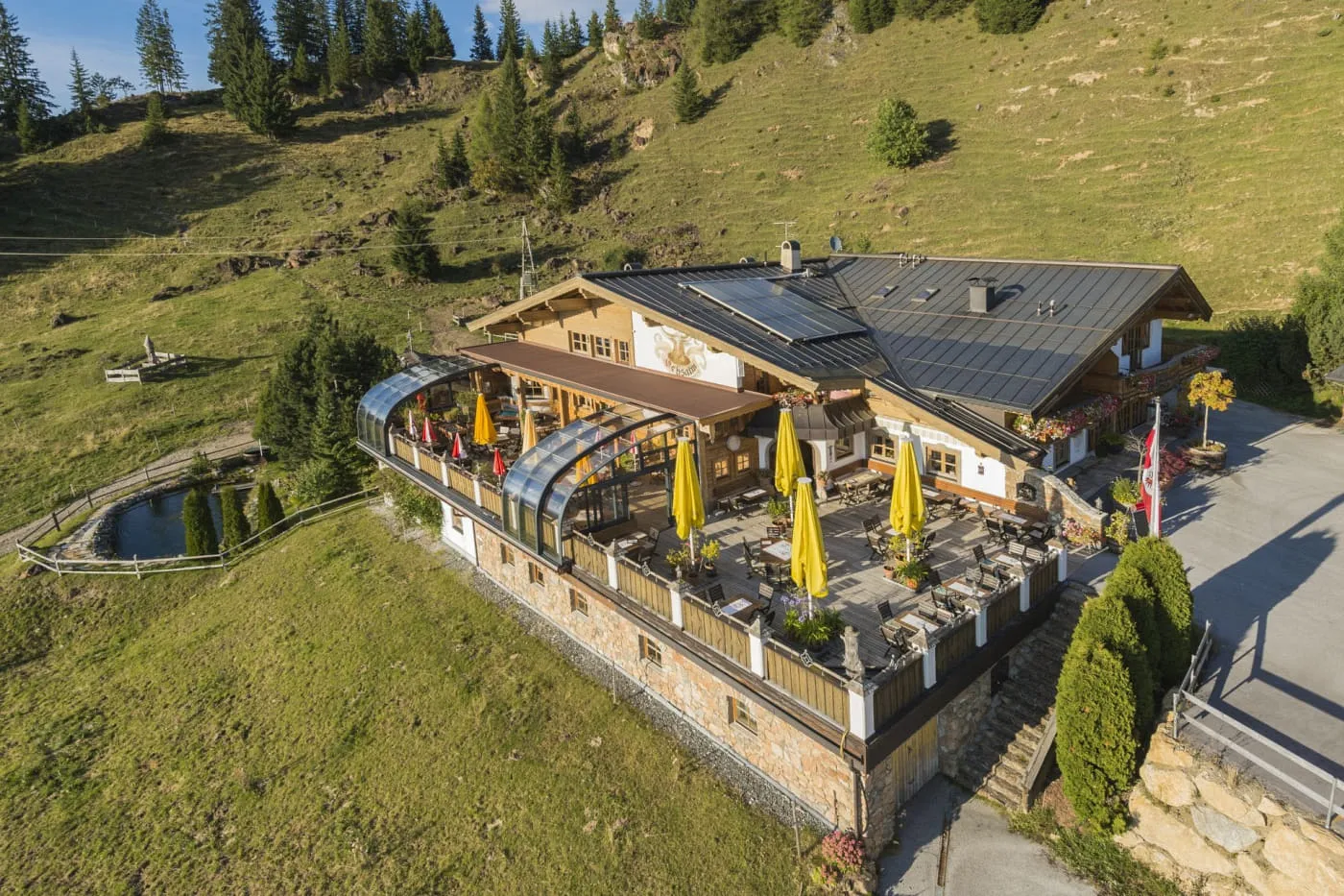 Gasthof OchsAlm mit Sonnenterrasse und Sonnenschirmen auf der Almwiese